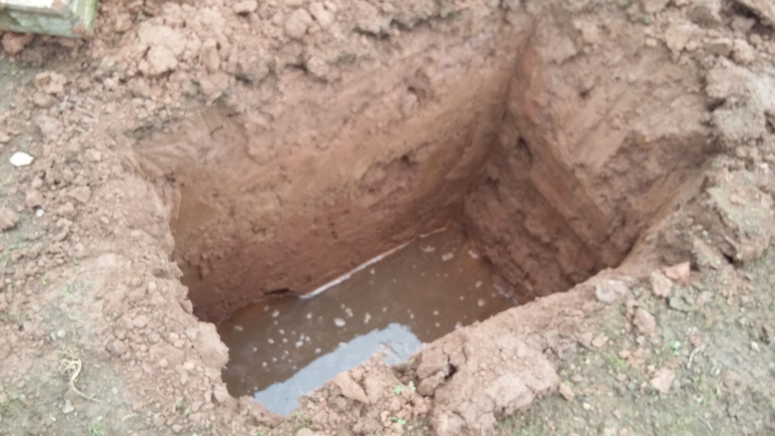 Soakaway trial hole being filled with water in Worcestershire