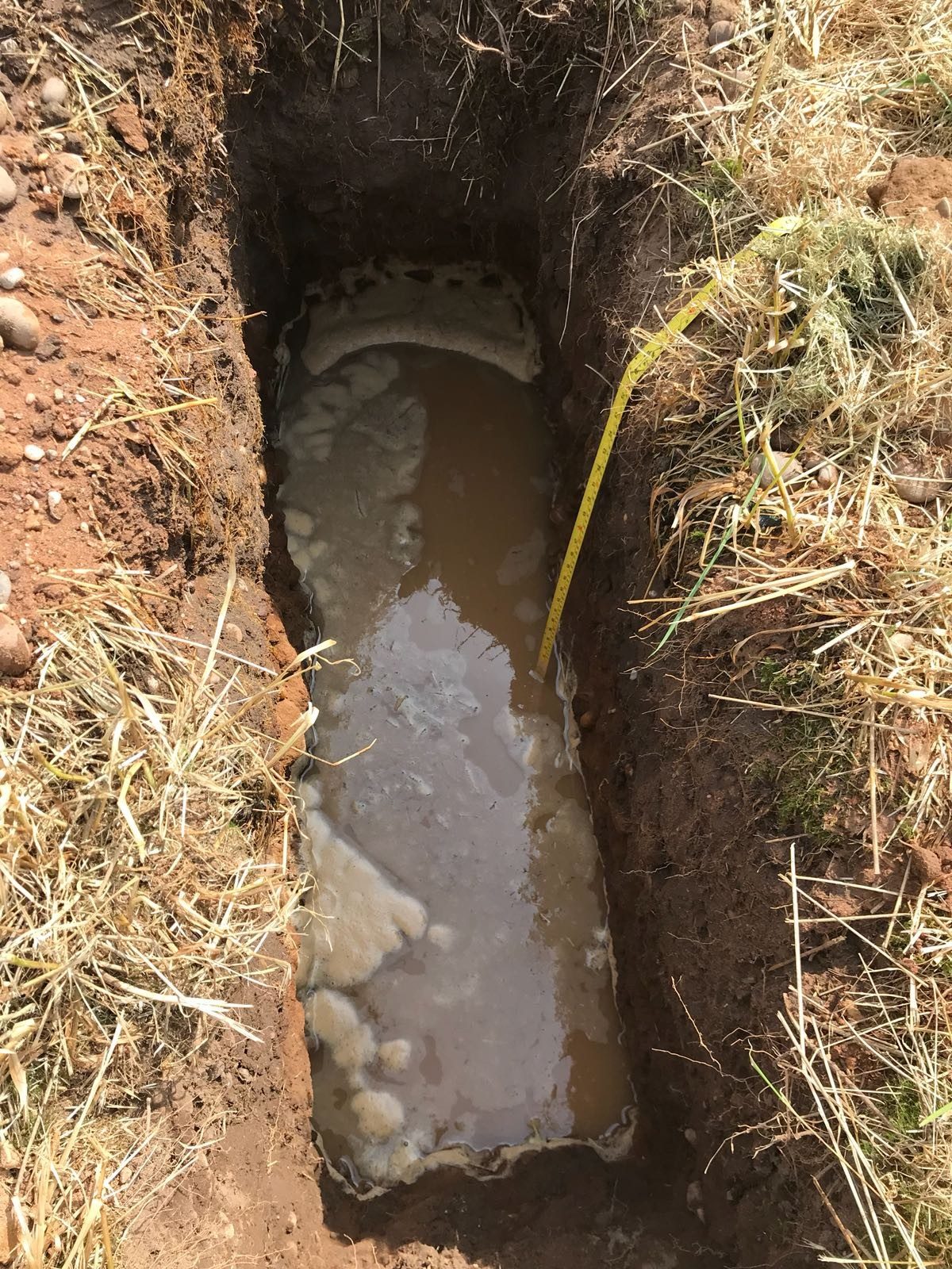 Soakaway trial hole being filled with water near Evesham